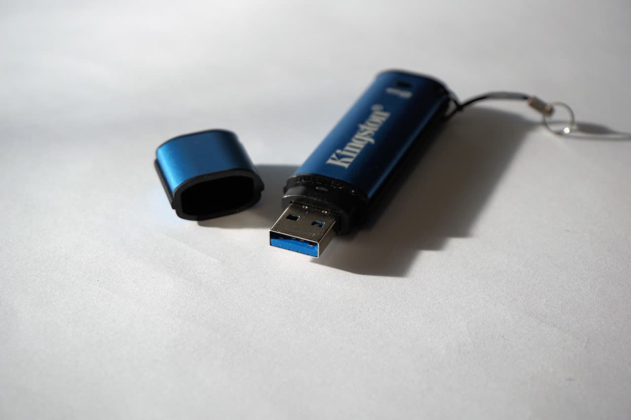 Uma pen USB numa secretária ao lado de um computador